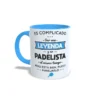 Taza de cerámica sobre pádel con frase es complicado ser una leyenda y un padelista al mismo tiempo, interior y asa en color azul claro, vista lateral izquierda.