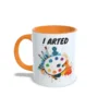 Taza de cerámica sobre pintura y arte con frase I arted, paleta de colores con pinceles y salpicaduras multicolor, interior y asa en color naranja, vista lateral izquierda.