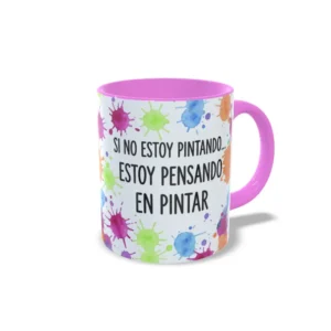 Taza de cerámica sobre pintura y arte con manchas de color y frase Si no estoy pintando, estoy pensando en pintar, interior y asa en color rosa, vista lateral derecha.