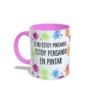 Taza de cerámica sobre pintura y arte con manchas de color y frase Si no estoy pintando, estoy pensando en pintar, interior y asa en color rosa, vista lateral izquierda.